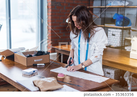 Young female fashion designer cutting fabric with 35363356