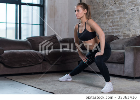 Attractive young woman training indoors doing side Attractive young woman training indoors doing side 35363410