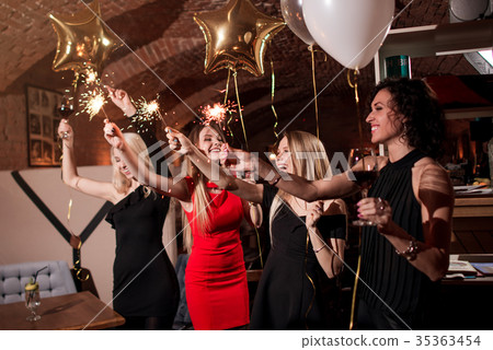 Happy pretty young women holding firework Happy pretty young women holding firework 35363454