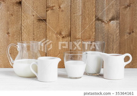 Various jugs and glasses with milk on the table 35364161