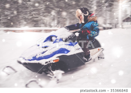 Boy driving snowmobile in a winter landscape 35366848
