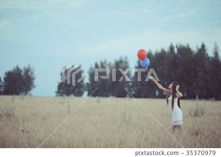 Dream, happiness - young girl in a field with flying balloons Dream, happiness - young girl in a field with flying balloons 35370979