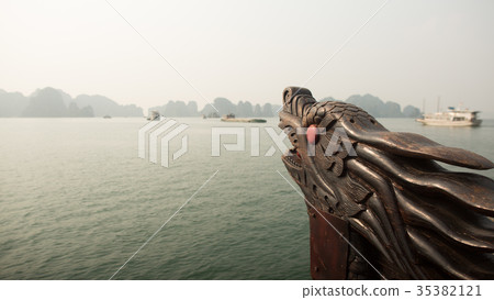 A boat with a dragon's head floating in the ocean 35382121