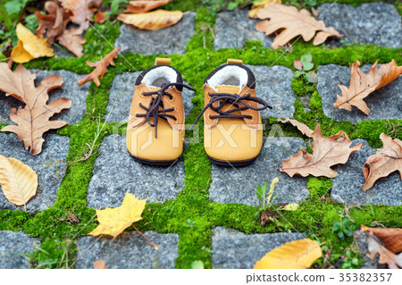 Baby boots in autumn park. Kid shoes with yellow 35382357