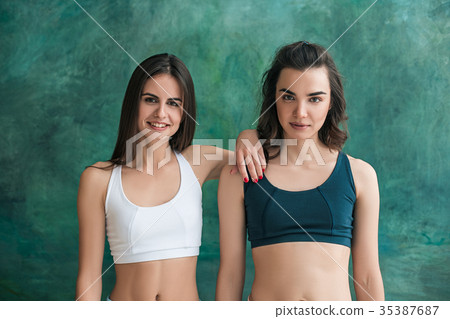 Two young sporty women posing at gym. Two young sporty women posing at gym. 35387687