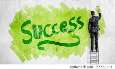 A businessman stands on a stepladder and paints a A businessman stands on a stepladder and paints a 35389273