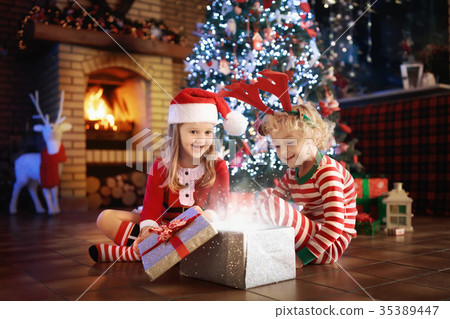 Child at Christmas tree. Kids at fireplace on Xmas Child at Christmas tree. Kids at fireplace on Xmas 35389447