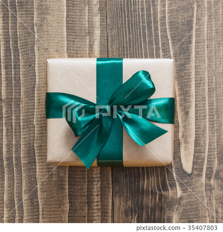 Gift box wrapped in craft paper with green ribbon. Gift box wrapped in craft paper with green ribbon. 35407803