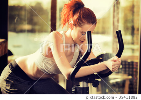 Active young woman doing exercise on bicycle Active young woman doing exercise on bicycle 35411882