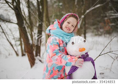 girl makes snowman in winter park girl makes snowman in winter park 35414853