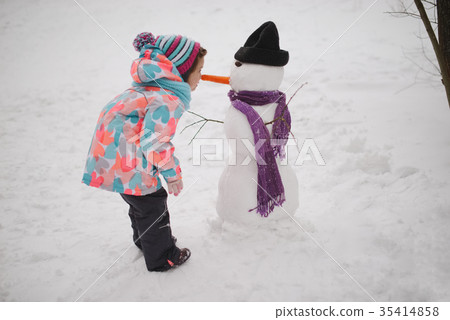girl makes snowman in winter park girl makes snowman in winter park 35414858