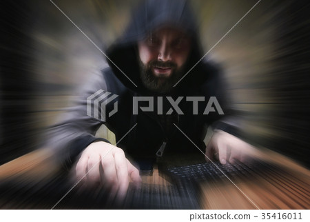 The hacker in the hood sits and works 35416011