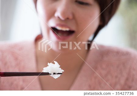 Middle-aged woman eating rice with chopsticks 35427736