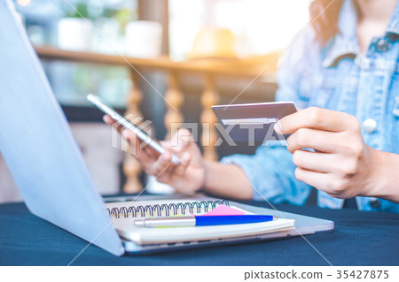 Women hold credit cards and use mobile phones 35427875