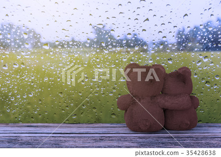 Teddy bear sitting at the window when it rains 35428638