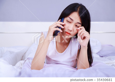 woman crying on the mobile phone on her bed in bedroom woman crying on the mobile phone on her bed in bedroom 35430681