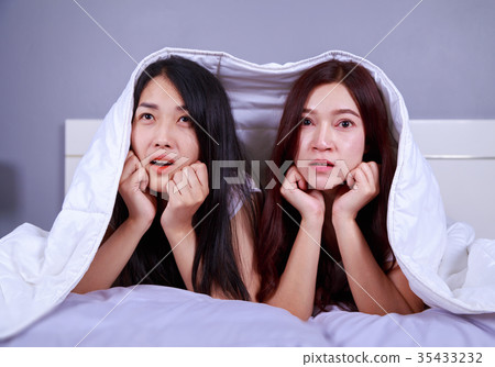 best friend woman on bed watching a tv with shocked expression o 35433232