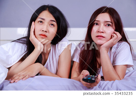 two best friends watching tv with remote on bed in bedroom two best friends watching tv with remote on bed in bedroom 35433235