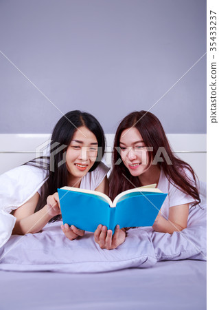 two woman reading a book on bed in bedroom two woman reading a book on bed in bedroom 35433237