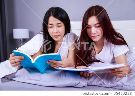 two woman reading a book on bed in bedroom two woman reading a book on bed in bedroom 35433238