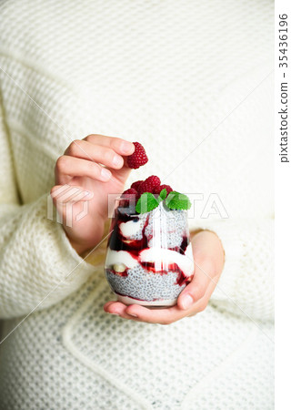 Girl in white sweater holds glass with chia milk 35436196