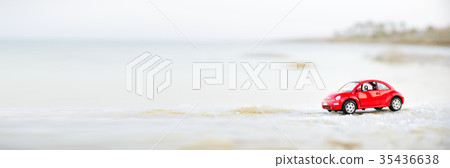 Travel concept. Red model toy car on sand near 35436638