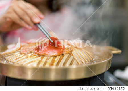 Hand holding chopstick with grilled korean pork  35439152