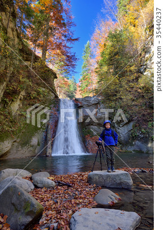 Kid with photo camera on tripod with a waterfall 35440237