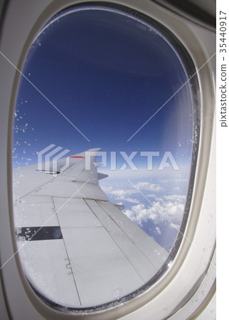 Sea of clouds and azure sky seen over the wing from an aircraft window flying at high altitude and freezing Sea of clouds and azure sky seen over the wing from an aircraft window flying at high altitude and freezing 35440917