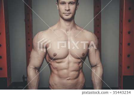 Handsome model young man posing in gym Handsome model young man posing in gym 35443234