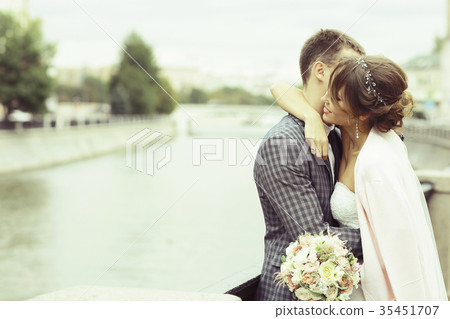 Kissing in the park the bride and groom newlyweds Kissing in the park the bride and groom newlyweds 35451707