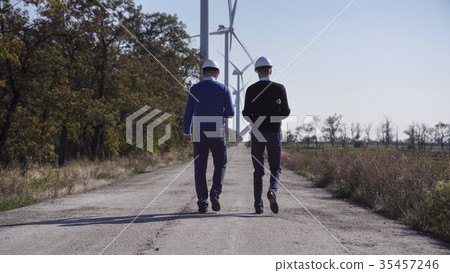 Two engineers walking towards wind farm Two engineers walking towards wind farm 35457246