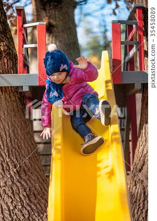 Happy three-year baby girl in jacket on slide Happy three-year baby girl in jacket on slide 35458089