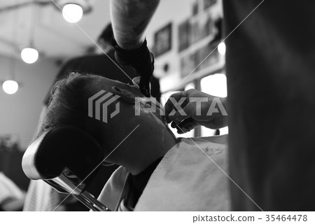 Hairdresser makes hairstyle a man with a beard 35464478