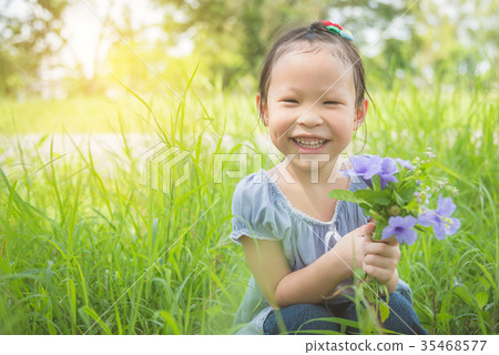 Little girl smiling while holding flower in graden 35468577