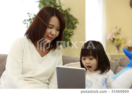 Mother operating a tablet with a child on the sofa Mother operating a tablet with a child on the sofa 35469909