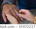 Bride hand and groom hand are wearing a ring. 35472217