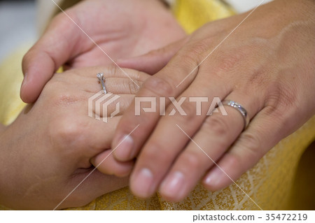 Bride hand and groom hand are wearing a ring. 35472219