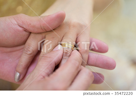 Bride hand and groom hand are wearing a ring. 35472220