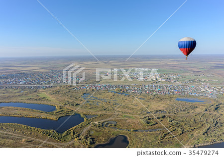 Flight of hot air balloon over rural landscape Flight of hot air balloon over rural landscape 35479274