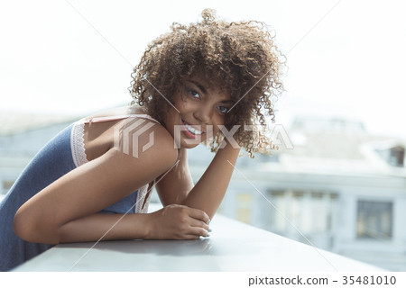 Beaming female situating on balcony 35481010