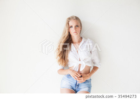 blonde girl with blue eyes in shorts on a white blonde girl with blue eyes in shorts on a white 35494273