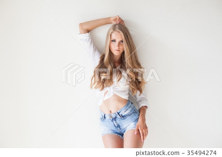 blonde girl with blue eyes in shorts on a white blonde girl with blue eyes in shorts on a white 35494274