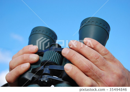 Binoculars in the hands of a man looking in sky Binoculars in the hands of a man looking in sky 35494846