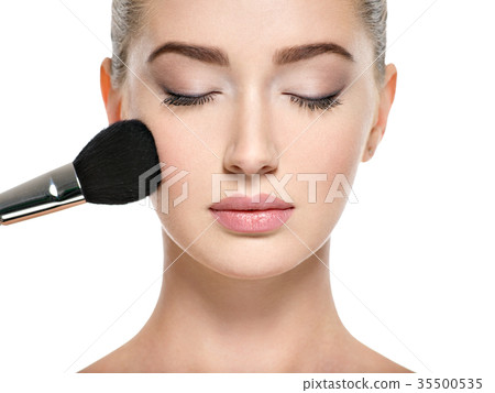 Young girl with makeup brush near at face Young girl with makeup brush near at face 35500535