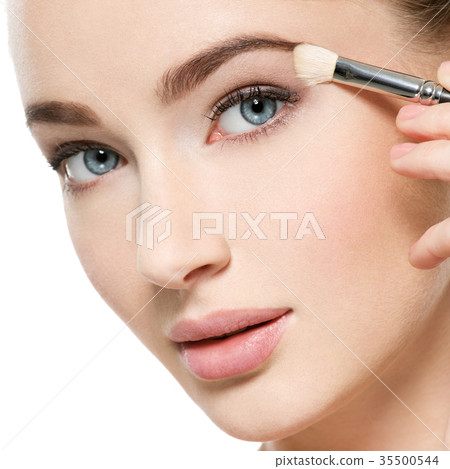 Girl makes makeup. Woman applies makeup shadow on the eyelid 35500544