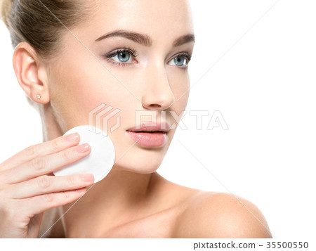 Girl removes makeup cotton ball from face Girl removes makeup cotton ball from face 35500550