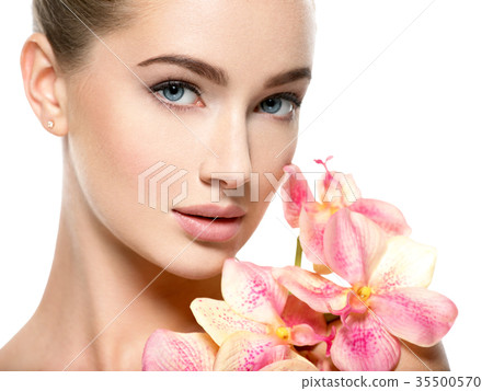 Beautiful young woman with flower in hand near at face. Beautiful young woman with flower in hand near at face. 35500570