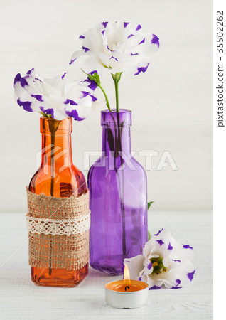 Purple eustoma flowers and lit candle Purple eustoma flowers and lit candle 35502262