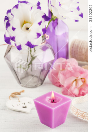 Purple eustoma flowers and lit candle Purple eustoma flowers and lit candle 35502265